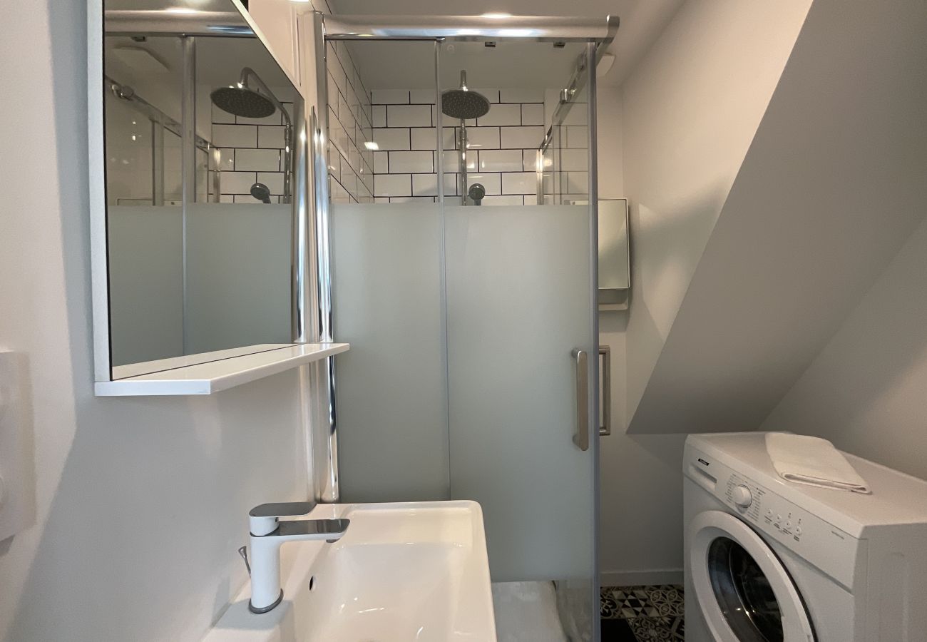 Cuarto de baño con ducha, tocador y lavadora. 